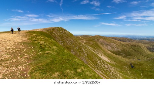 Couple Of Young Man And Woman Walking Over The Helvellyn Peak, Lake District, Cumbria, England