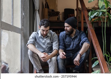 Couple of young men talking on the stairs of an office - Powered by Shutterstock