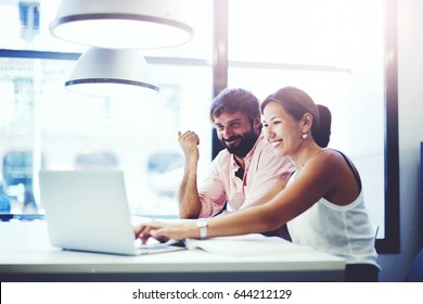 Couple Of Young Office Professionals Talking Over A Laptop Computer, Two Business People Discussing Ideas In Co-working Space With A Laptop Or Notebook In Front Of Them, Students Working With Laptop