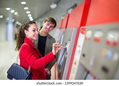 Couple Of Young Passengers Buying Subway Ticket At Terminal
