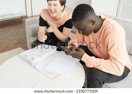 Couple of young people doing house paperwork together on a coach