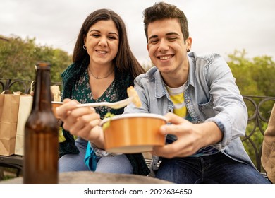 Couple of young people eating outdoors on plastic free paper bowls