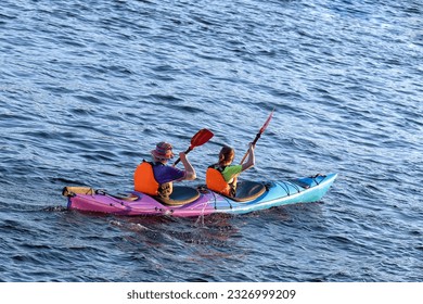 A couple of young people are kayaking on the water. Young family on active vacation. - Powered by Shutterstock