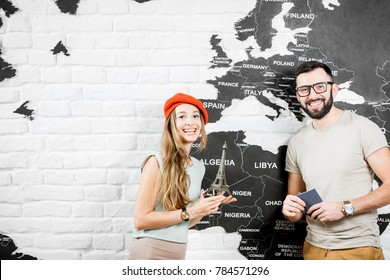 Couple Of A Young Travelers Standing Near The Wall With World Map, Dreaming About A Summer Vacations In Paris