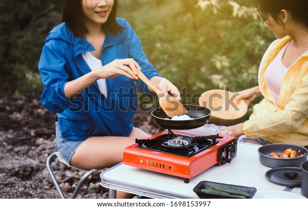 Couple young women\
friends cooking food on stove for dinner at outdoor\
together,Enjoying camping\
concept
