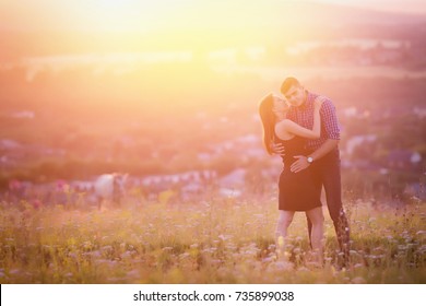 Couplein love romantic lovers kissing, hugging at sunset, background of mountains and fog, sun, clouds in fiery red, orange colors. Concept wedding, first kiss, date