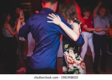 Couples dancing traditional latin argentinian dance milonga in the ballroom, tango salsa bachata kizomba lesson in the red, purple and violet lights, dance festival 