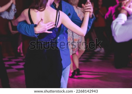 Couples dancing traditional latin argentinian dance milonga in the ballroom, tango salsa bachata kizomba lesson in the red and purple lights, festival, lesson class in dance school class academy
