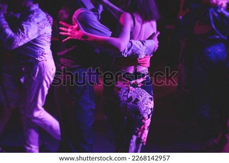 Couples dancing traditional latin argentinian dance milonga in the ballroom, tango salsa bachata kizomba lesson in the red and purple lights, festival, lesson class in dance school class academy
