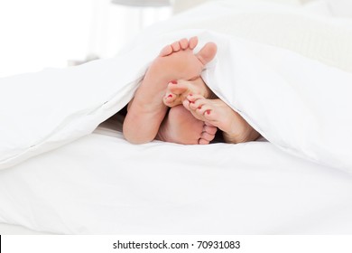 Couple's Feet In The Bed