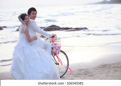 couples of groom and bride riding a bicycle on beach
