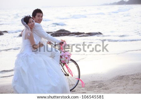 couples of groom and bride riding a bicycle on beach