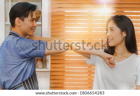 Couples have fun teasing together in the kitchen, hitting their elbows to avoid the spread of the coronavirus, greeting them with a hug or a handshake. Don't shake hands inside the house