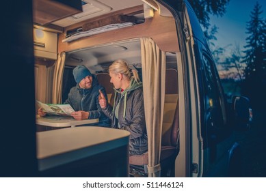 Couples And The RV Park Camping. Young Couples Planning Next Trip In The Motorhome.