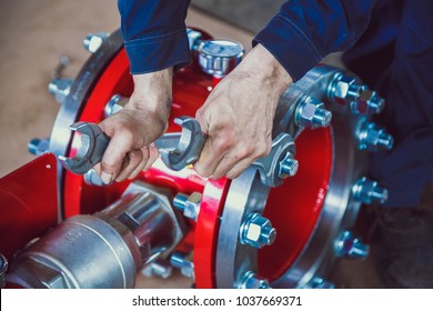 Coupling Flange. The Worker Tightens The Bolts On The Red Coupling Sleeve With A Wrench. Close-up