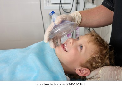 Courageous boy smiles and looks at the doctor before the operation on the operating table. Pediatric anesthesiologist applies an oxygen mask to a cheerful child before surgery - Powered by Shutterstock