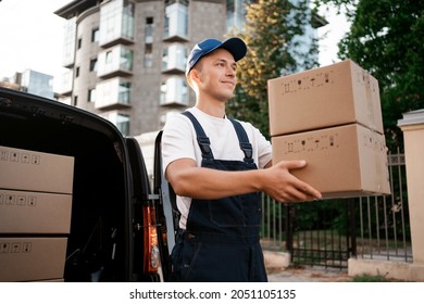 The courier brought the delivery of the box to the client. Courier service employee in uniform. - Shutterstock ID 2051105135