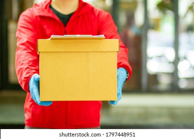 The Courier Carried A Cardboard Box Wearing Rubber Medical Gloves. Fast Package Delivery To Your Doorstep.