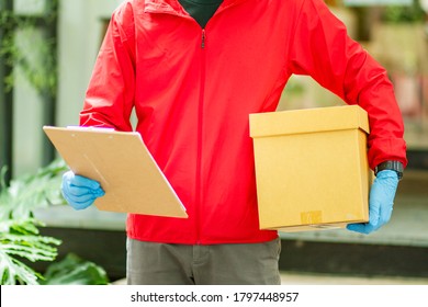 The Courier Carried A Cardboard Box Wearing Rubber Medical Gloves. Fast Package Delivery To Your Doorstep.