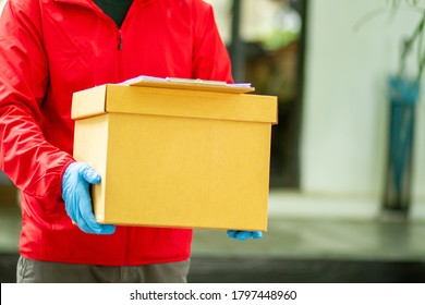 The Courier Carried A Cardboard Box Wearing Rubber Medical Gloves. Fast Package Delivery To Your Doorstep.