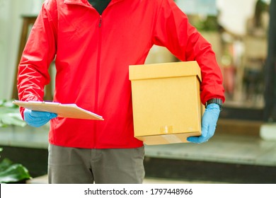 The Courier Carried A Cardboard Box Wearing Rubber Medical Gloves. Fast Package Delivery To Your Doorstep.