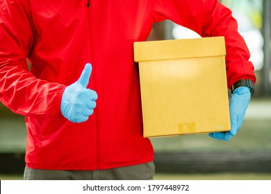 The Courier Carried A Cardboard Box Wearing Rubber Medical Gloves. Fast Package Delivery To Your Doorstep.