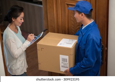 Courier Carrying Large Parcel While Woman Confirming Delivery