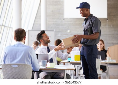 Courier Collecting Package From Businessman In Busy Office