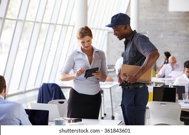 Courier Collecting Package From Businesswoman In Busy Office