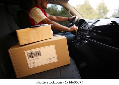 Courier driving delivery van, focus on parcels and clipboard