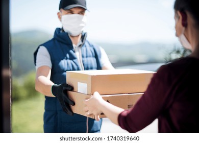 Courier with face mask delivering parcel, corona virus and quarantine concept. - Powered by Shutterstock