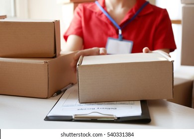 Courier hands giving packaged parcel at table