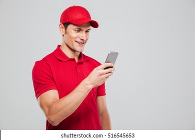 Courier looking at phone in studio. smiling man. isolated gray background