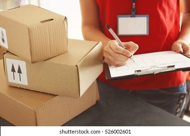 Courier Making Notes In Delivery Receipt At Table