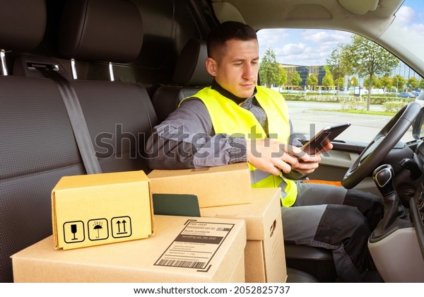 Courier man. Delivery service worker. Courier in\
driver seat. Man with cardboard boxes in car. Courier is engaged in\
delivery of pasta. Young deliveryman inside car. Delivery service\
career concept