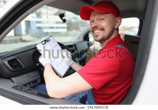 Courier man
filling out documents on clipboard in
car