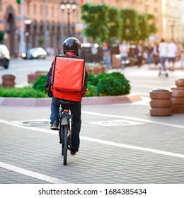 Courier On Bicycle In Protective Helmet Delivering Food In The City. Delivery Boy On Bike Deliver Tasty Food. Food Delivery Service. Online Ordering.