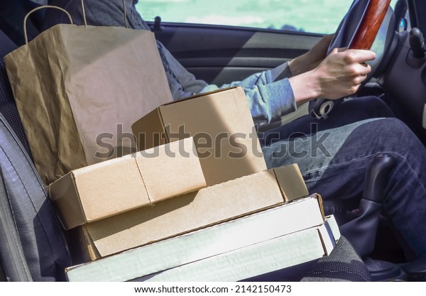 Courier with parcels in the car. Delivery of\
parcels, goods, pizza. Deliveryman. Safe delivery during\
coronavirus quarantine.