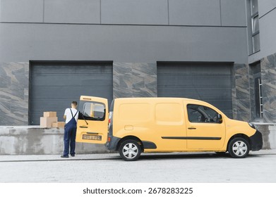 Courier preparing parcels for delivery, loading cardboard boxes into a yellow van parked outside a warehouse