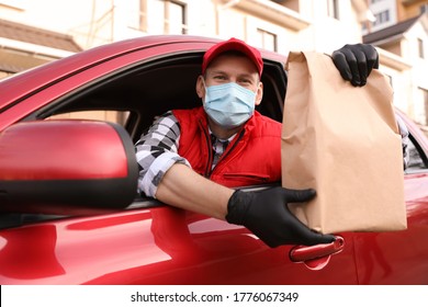 Courier In Protective Mask And Gloves Giving Order Out Of Car Window Outdoors. Food Delivery Service During Coronavirus Quarantine