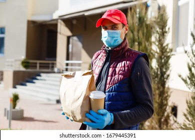 Courier in protective mask and medical gloves delivers takeaway food. Delivery service under quarantine, disease outbreak, coronavirus covid-19 pandemic conditions. - Powered by Shutterstock