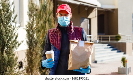 Courier In Protective Mask And Medical Gloves Delivers Takeaway Food. Delivery Service Under Quarantine, Disease Outbreak, Coronavirus Covid-19 Pandemic Conditions.