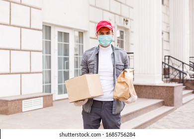 Courier In Protective Mask And Medical Gloves Delivers Takeaway Food. Delivery Service Under Quarantine, Disease Outbreak, Coronavirus Covid-19 Pandemic Conditions.