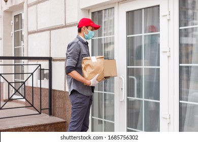 Courier In Protective Mask And Medical Gloves Delivers Takeaway Food. Delivery Service Under Quarantine, Disease Outbreak, Coronavirus Covid-19 Pandemic Conditions.