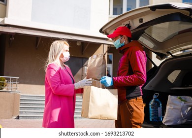 Courier In Protective Mask And Medical Gloves Delivers Takeaway Food. Delivery Service Under Quarantine, Disease Outbreak, Coronavirus Covid-19 Pandemic Conditions.