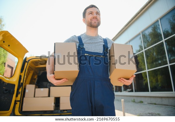 Courier service for the delivery of goods. Express\
service a man in a uniform delivers boxes. The employee carries the\
order home to the\
client