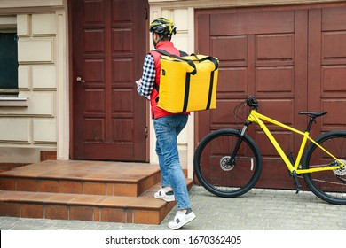 Courier with thermo bag and clipboard near customer's house. Food delivery service