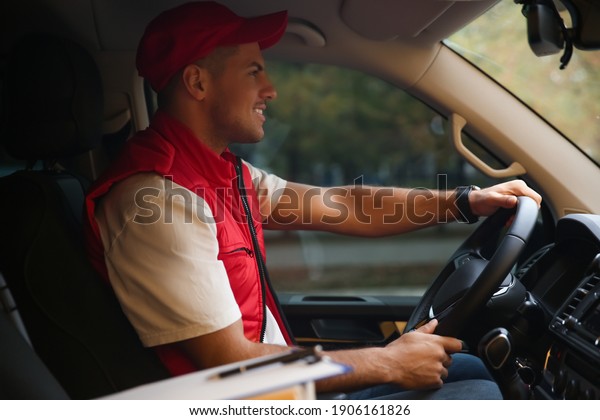 Courier in uniform on\
driver\'s seat of car