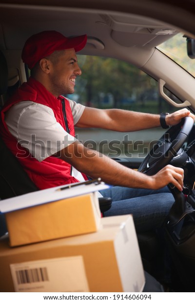 Courier in uniform on\
driver\'s seat of car