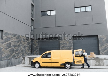 Courier unloading parcels from an open delivery van outside a warehouse building, managing logistics and shipping operations in an urban setting
